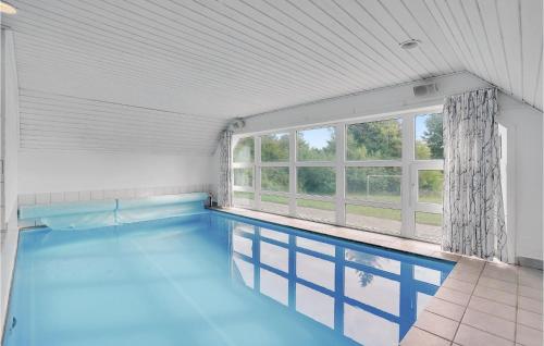 a swimming pool with blue water in a room with windows at Beautiful Home In Rømø With Sauna in Rømø Kirkeby