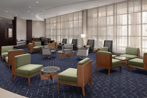 a waiting room with chairs and tables and windows at Courtyard Syracuse Downtown at Armory Square in Syracuse