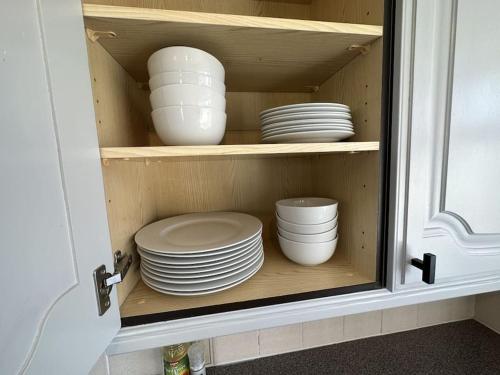 a cupboard with plates and bowls in it at Stylish 3-Bedroom House with Garden & Free Parking's, Prime location with private garden in Kidlington