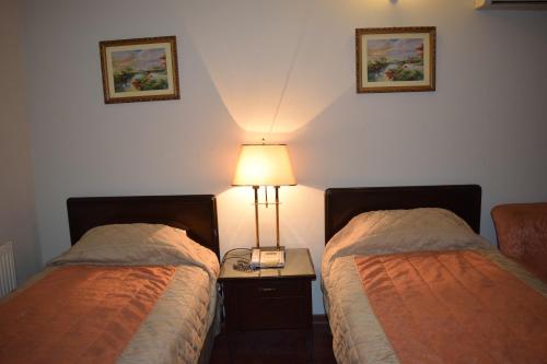 a bedroom with two beds and a lamp on a table at Carlton Tower Hotel Lahore in Lahore