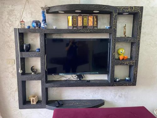 a black entertainment center with a television on a wall at Happy Sweet Inn in Irbid