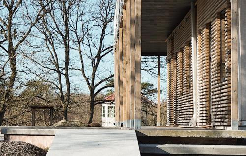 a building with wooden columns and windows with trees at Cozy Home In Vallda With Kitchen in Vallda