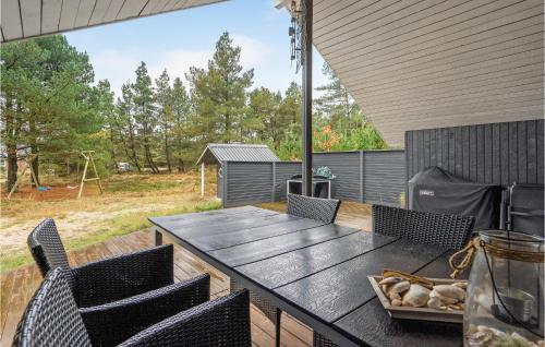 un patio con tavolo e sedie nere e un parco giochi di Three-Bedroom Holiday Home In Romo a Mølby