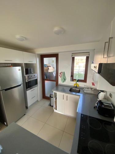 a kitchen with a stainless steel refrigerator and white cabinets at Departamento Puerto Velero in Tongoy