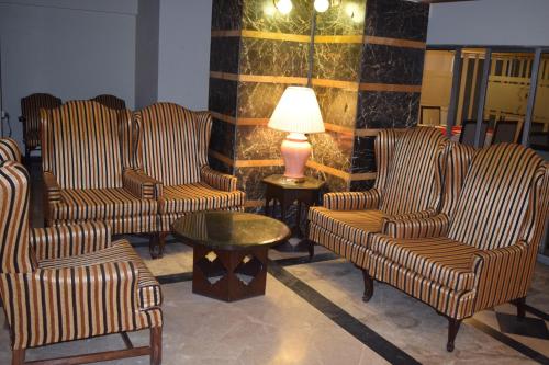 a lobby with chairs and a table and a lamp at Carlton Tower Hotel Lahore in Lahore