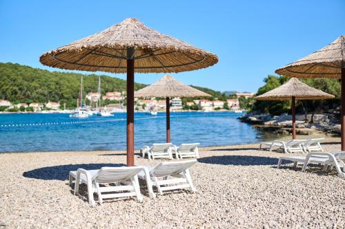 a group of chairs and umbrellas on a beach at Aminess Vival Port9 Residence in Korčula