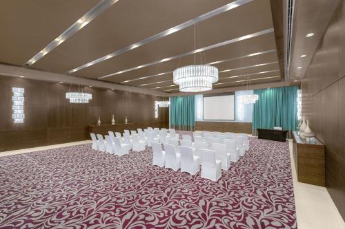 a conference room with white chairs and a podium at Four Points by Sheraton Al Ain in Al Ain