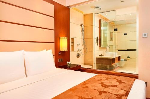 a bedroom with a bed and a bathroom with a sink at Courtyard by Marriott Kochi Airport in Nedumbassery