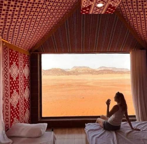 a woman sitting on a bed looking out of a window at Mars moon camp in Wadi Rum
