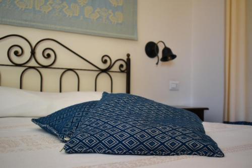 a bed with a blue pillow on top of it at Giardini Malaspina in Bosa