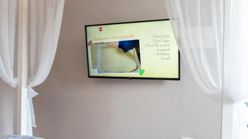 a flat screen tv hanging on a wall with curtains at Giardini Malaspina in Bosa