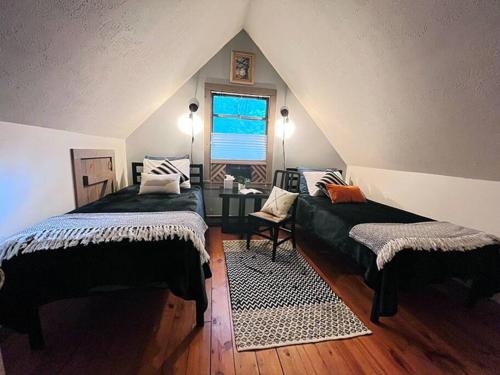 a attic bedroom with two beds and a window at Treetop Cabin in Cedar Mountain