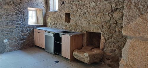 a stone walled kitchen with a stove and a sink at O Celeiro - Espaço Rural in Tougues