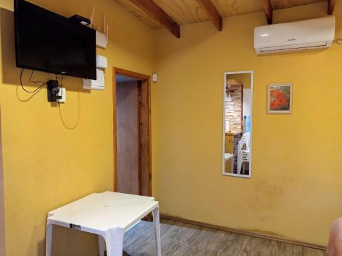 a living room with a tv on a yellow wall at Chalet Volga - Punta Del Diablo - Departamento de Rocha in Punta Del Diablo