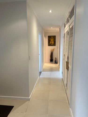 a hallway with white walls and a tile floor at The Ducks Nest - Ocean Retreat in Safety Bay