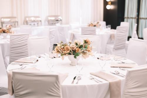 a room with white tables with white chairs and flowers at Courtyard by Marriott Calgary South in Calgary