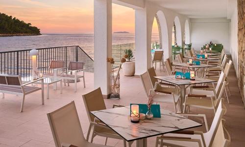 a restaurant with tables and chairs and the ocean at Aminess Younique Lume Hotel in Brna