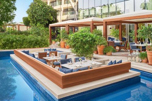 an outdoor restaurant with tables and chairs next to a pool at The Abu Dhabi EDITION in Abu Dhabi