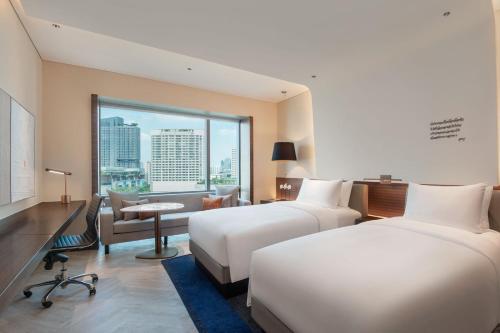 a hotel room with two beds and a large window at Le Meridien Bangkok in Bangkok