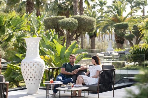 a man and woman sitting in chairs in a garden at The Ritz-Carlton Rabat, Dar Es Salam in Rabat