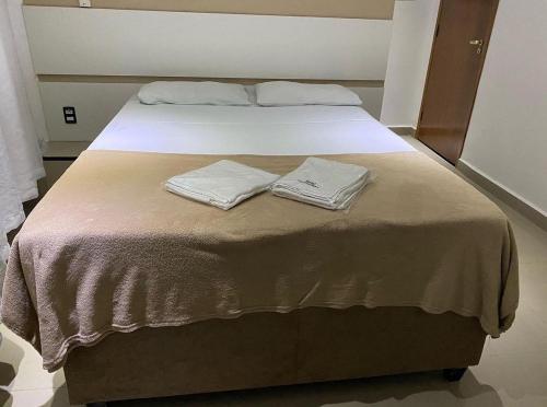 a bed with two towels sitting on top of it at Hotel Guarulhos in Sao Paulo