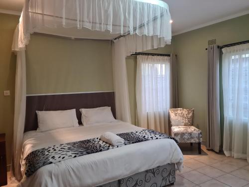 a bedroom with a large bed and a chair at The Cottage in Lilongwe
