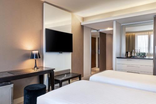a hotel room with two beds and a mirror at AC Hotel Paris Porte Maillot by Marriott in Paris