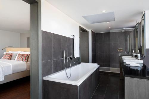 a bathroom with a bath tub and a bed at Le Meridien Nice in Nice