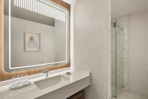 a bathroom with a sink and a mirror and a shower at Hotel Cleveland Autograph Collection in Cleveland