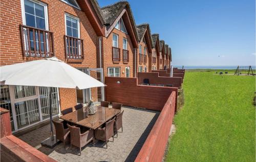 a patio with a table and an umbrella in front of a building at Three-Bedroom Holiday Home In Romo in Kongsmark