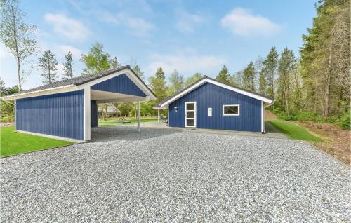 a blue garage with a gravel driveway at Holiday Home Hybenvangen Oksbøl Denm in Oksbøl