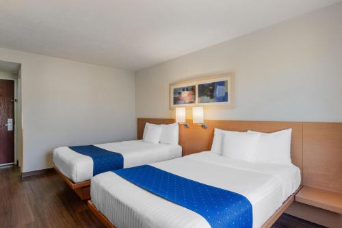 a hotel room with two beds with blue sheets at City Express by Marriott Tuxtla Gutiérrez in Tuxtla Gutiérrez
