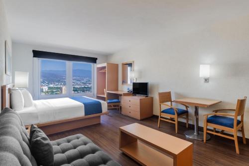 a hotel room with a bed and a couch and a table at City Express by Marriott Tuxtla Gutiérrez in Tuxtla Gutiérrez
