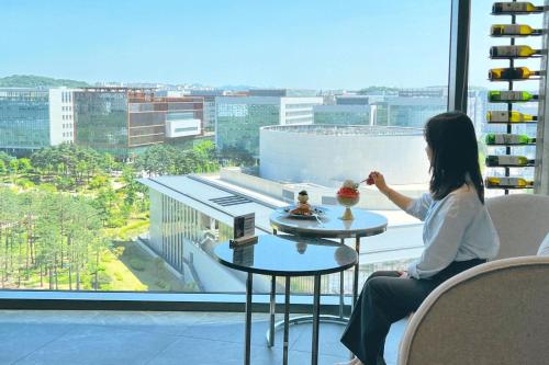 a woman sitting at a table in front of a window at Courtyard by Marriott Seoul Botanic Park in Seoul