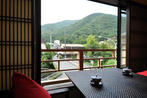 a balcony with a table and a view of a mountain at Hakone Onsen Ryokan Yaeikan in Hakone