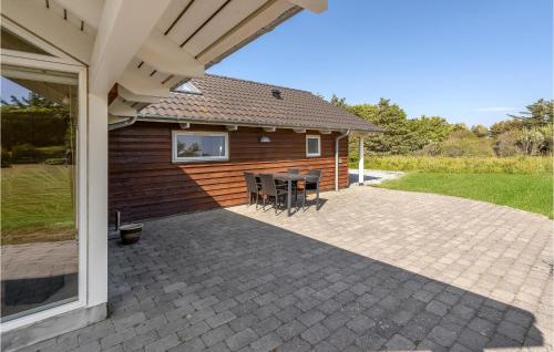 a patio with a table and chairs in front of a house at Awesome Home In Løkken With Sauna in Løkken