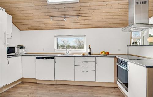 a kitchen with white cabinets and a wooden ceiling at Awesome Home In Løkken With Sauna in Løkken