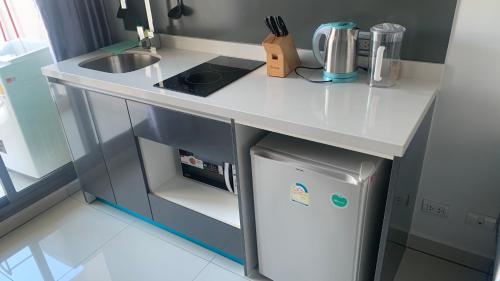 a small kitchen with a white counter top and a refrigerator at Arcadia beach 网红水系公寓一房 Nice view 专业的健身房 桑拿 中心位置 交通便利 Smart tv WiFi in Pattaya South