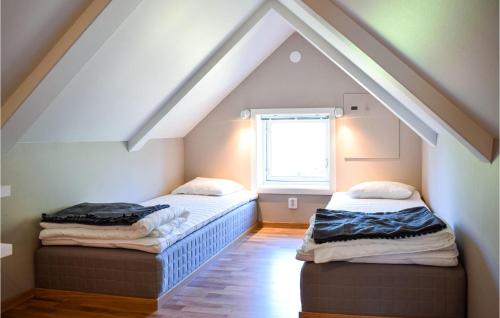 two beds in a attic room with a window at 2 Bedroom Awesome Home In Rockneby in Rockneby