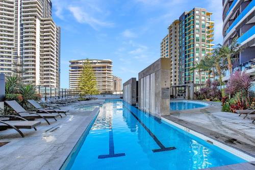 a large swimming pool with chairs and buildings at Stunning 2 bed 2 bath 8th floor - GC Getaways in Gold Coast