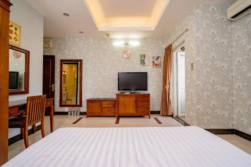 a bedroom with a bed and a tv and a desk at Ben Thanh Retreats Hotel in Ho Chi Minh City