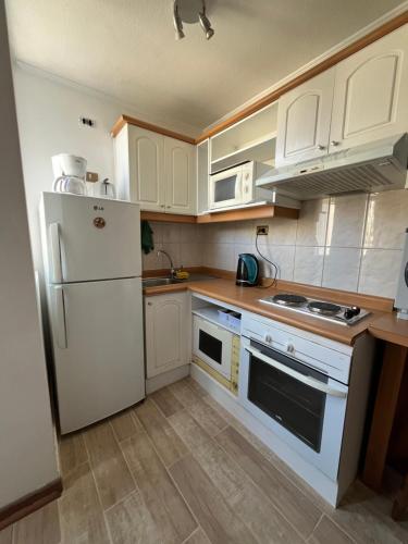 eine Küche mit weißen Schränken und einem weißen Kühlschrank in der Unterkunft Studio Cochrane in Santiago