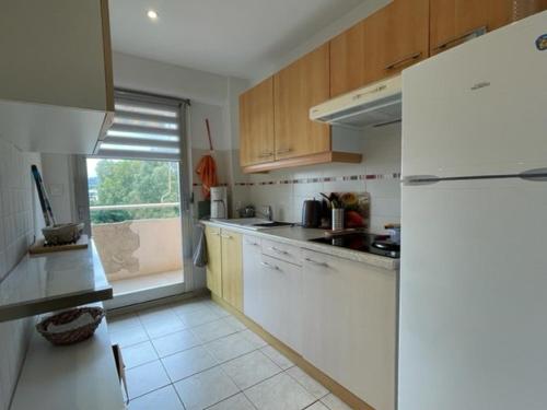 une cuisine avec des armoires en bois et un réfrigérateur blanc dans l'établissement Appartement Climatisé 2 Étoiles avec Balcon, Proche Plage et Centre - Le Lavandou - FR-1-308-199, au Lavandou