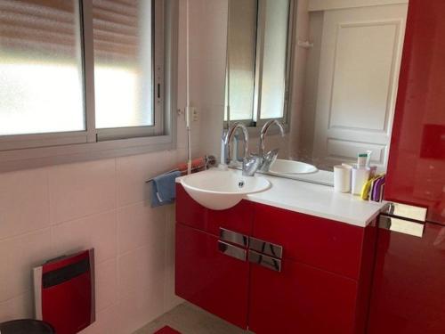 La salle de bains est pourvue d'un lavabo et d'une armoire rouge. dans l'établissement Appartement Climatisé 2 Étoiles avec Balcon, Proche Plage et Centre - Le Lavandou - FR-1-308-199, au Lavandou