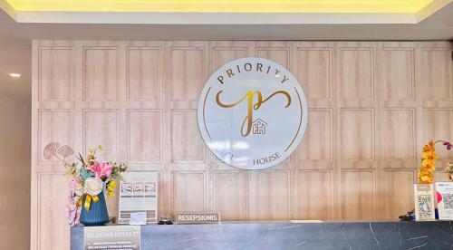 un cartello su una parete di legno con dei fiori su un bancone di Priority Guest House Samarinda a Samarinda