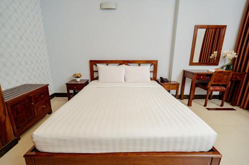 a bedroom with a large white bed and a desk at Ben Thanh Retreats Hotel in Ho Chi Minh City