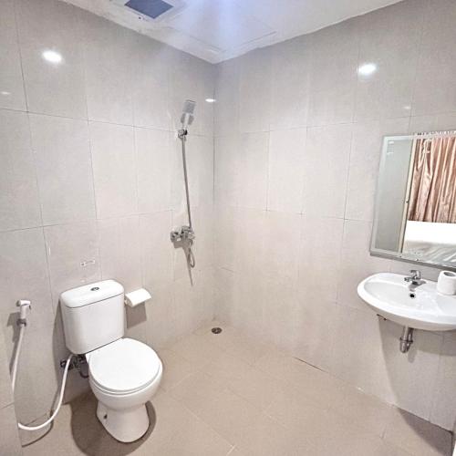 a white bathroom with a toilet and a sink at Priority Guest House Samarinda in Samarinda