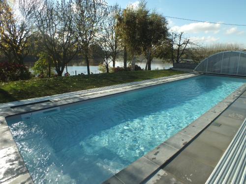 una piscina de agua azul y una casa de cristal en Gîte - La Rigaudière, en Le Theil-de-Bretagne