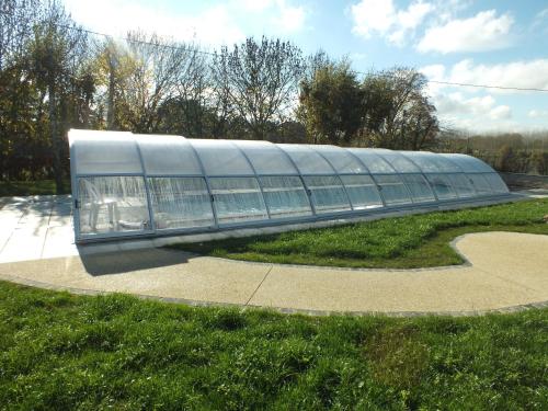 a large glass building sitting on top of a grass field at Gîte - La Rigaudière in Le Theil-de-Bretagne