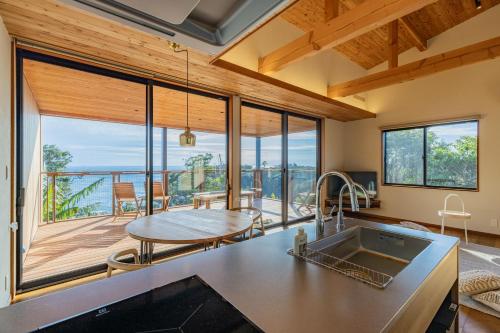a kitchen with a table and a large window at ガーデンヴィラ白浜　KOTI in Shimoda